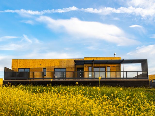 A wooden house with a deck and flowers in the yard at Signature Lodge 4 Redruth