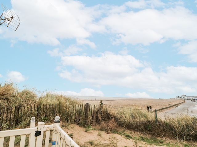A view of sand and sea with grass and a fence at 37 Redcar