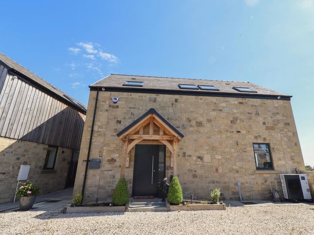 An entrance of a house with a wooden door and windows at The Joiners Cottage in Birling near Warkworth