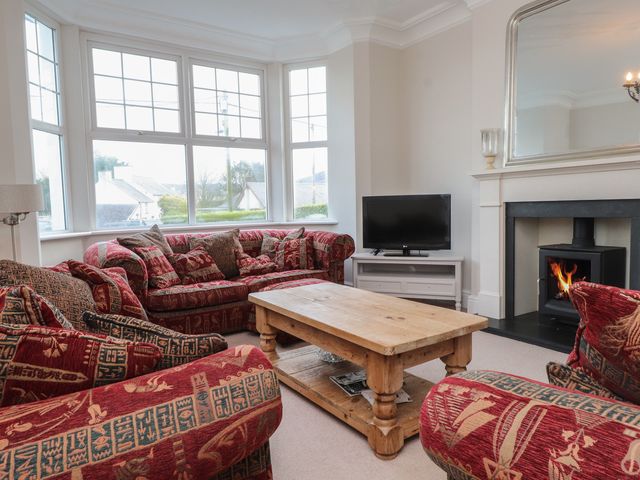 A living room with a TV, coffee table, and sofa at Bryniau Pwllheli
