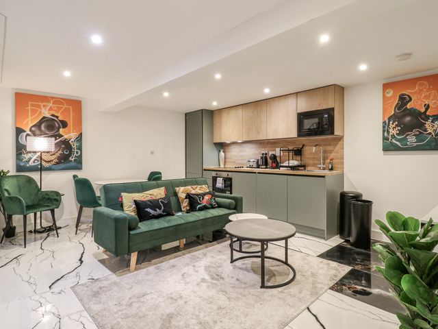A living room with a sofa and kitchen units at 2A Ruby Street Southwark London