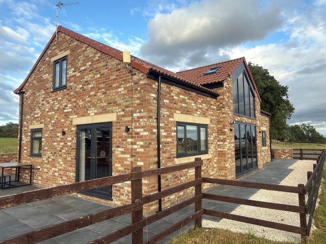A house with brick exterior and patio at Westholme Country Lodge Thirsk