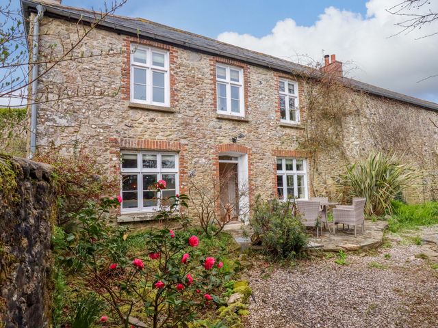 An outdoor area with a stone house and patio furniture at The Mill House in Newton Abbot