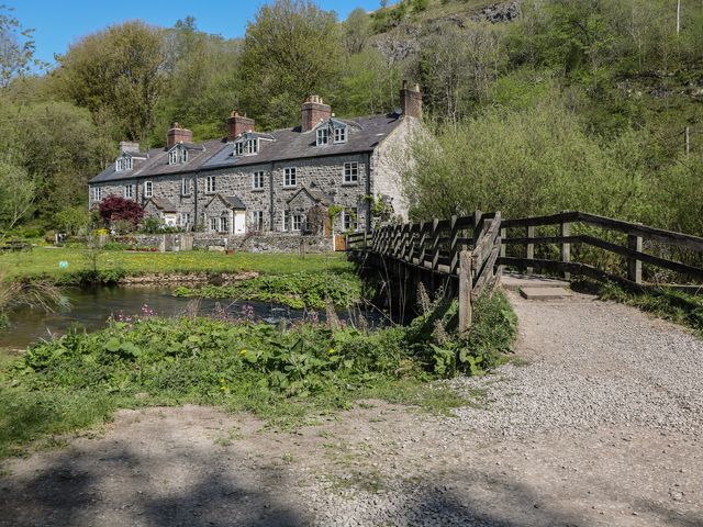 A row of stone cottages with a bridge over a river at Honeysuckle Cottage 