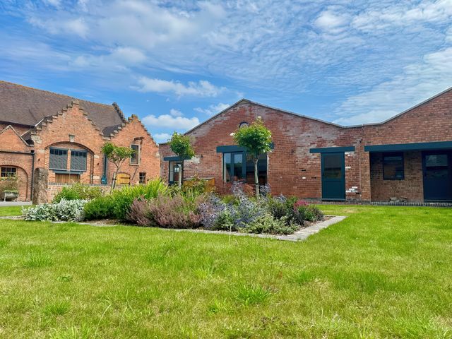 A brick building with grass and flowers at Courtyard View in Ashbourne