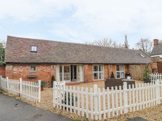 A house with outdoor seating and a white fence at Megs Cottage in Stratford-upon-Avon