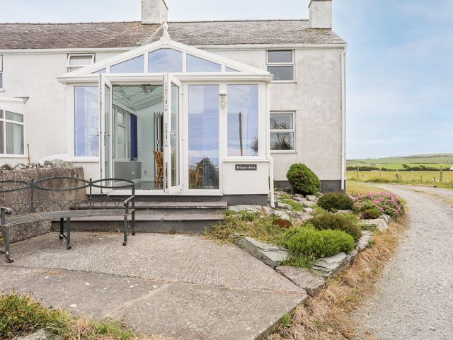 An outdoor view of a house with a conservatory at Bodlasan Groes Cottage in Holyhead