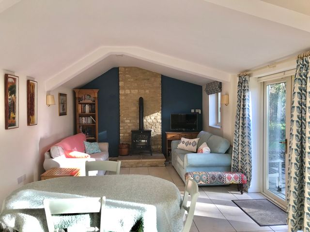 A living room with a fireplace and a bookshelf at Meadow Lodge in Cerney Wick near South Cerney, Cotswolds