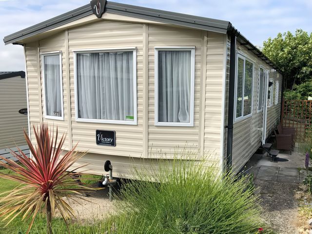 A mobile home with a sign on the side and plants at Swanage Bay View in Swanage
