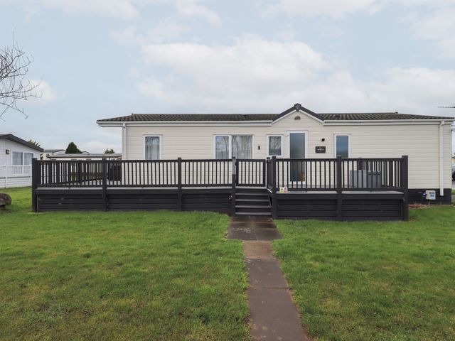 A modular home with a deck and grass area at Lily's Lodge in Morecambe