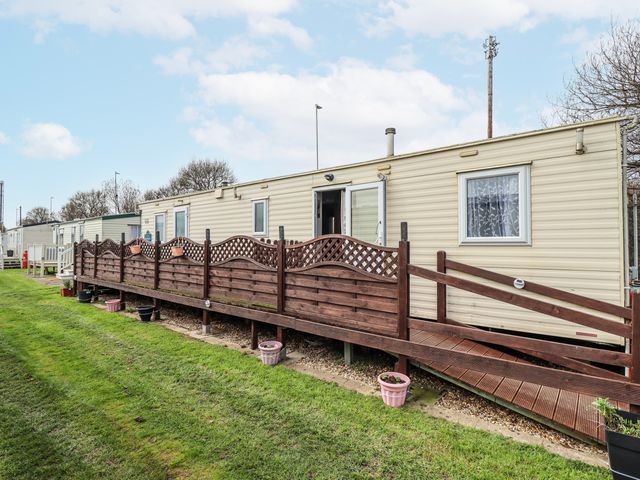 An outdoor area with a mobile home and wooden deck with fence at The Promenade in Skegness