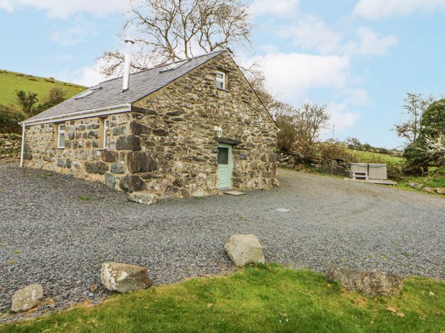 A stone house with gravel path and outdoor area at Little Barn near Criccieth