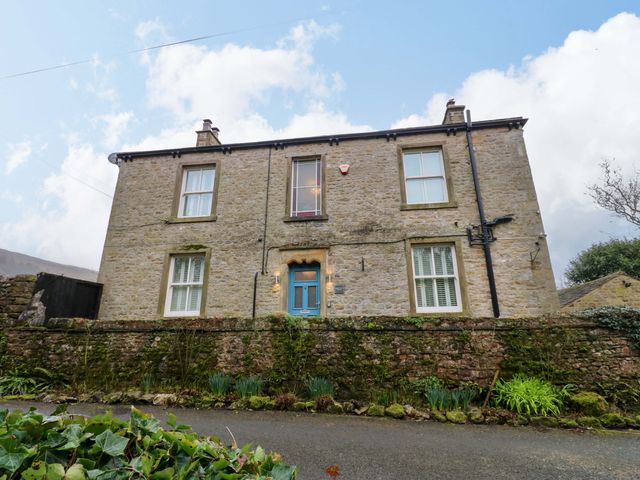 A house with stone walls and a blue door at Langcliffe House in Kettlewell