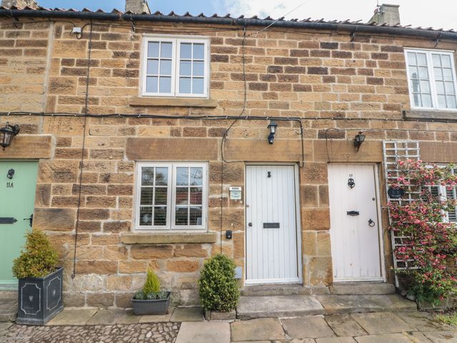 An exterior view of a stone cottage with doors and plants at Isla cottage