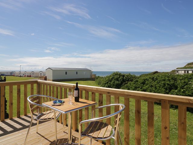 A balcony with a table and chairs overlooking the sea at The Plover in St Bees
