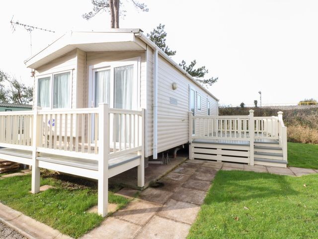 A caravan with a deck and steps at Under cliff caravan in Ferryside