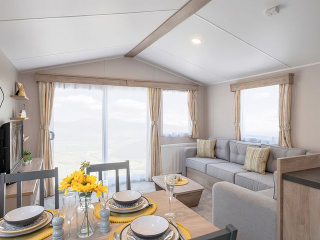 A living room with a couch and dining table at 554 Pentreath View in Perranporth