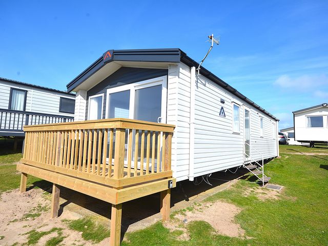 A caravan with a deck and steps at 554 Pentreath View Perranporth