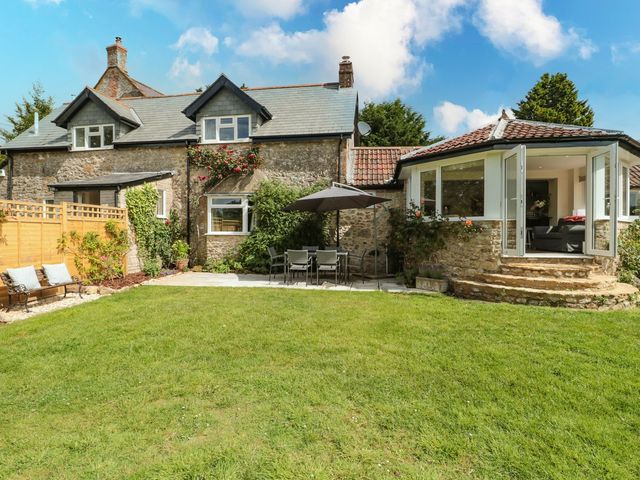 A garden with a table and chairs in front of a house at Ammerham Farm Cottage Ammerham near Winsham