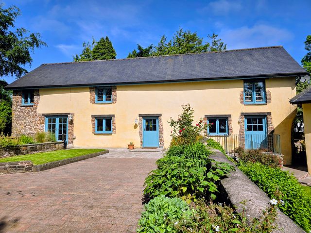 A house with windows and a door in an outdoor area at Pylemoor Cottage in Washfield near Tiverton