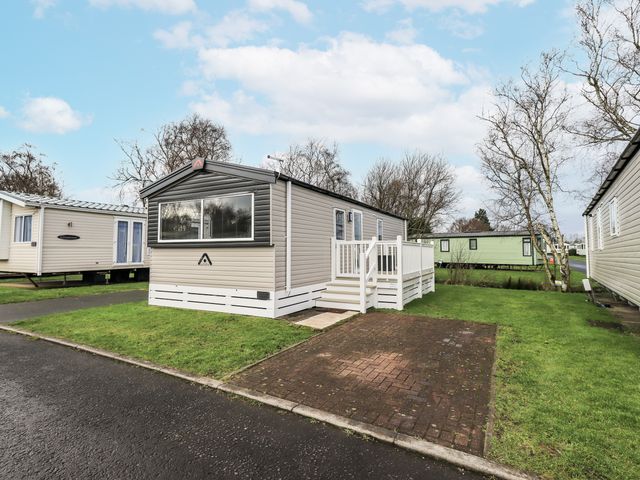A park home with a decking area and grass at Hadrian's Rest in Wigton