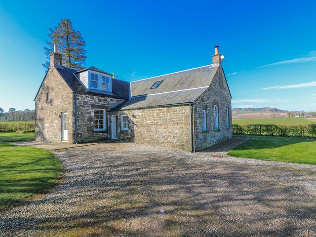 A house with a stone exterior and driveway at Meadowgreen Farmhouse Forfar