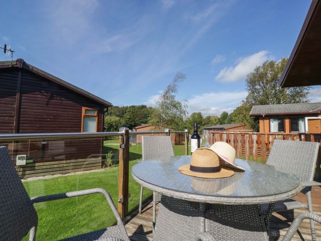 An outdoor seating area with a table and chairs at South Lakeland Lodge. No. 46 Gressingham near Carnforth
