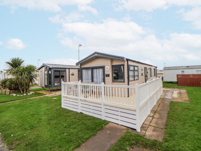 A caravan with decking and a fence at Chappie's Caravan 2.0 Rhyl