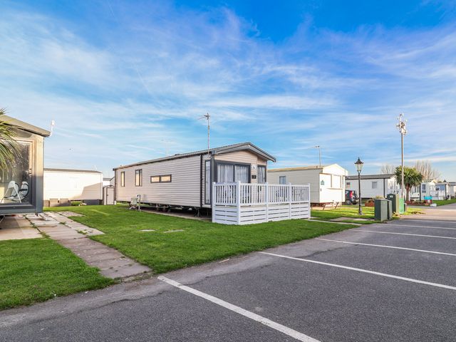 A caravan with a deck and grass area at Chappie's Caravan 2.0 Rhyl
