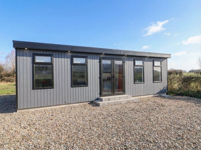A house with grey exterior and front steps at Binevenagh Point Cabin