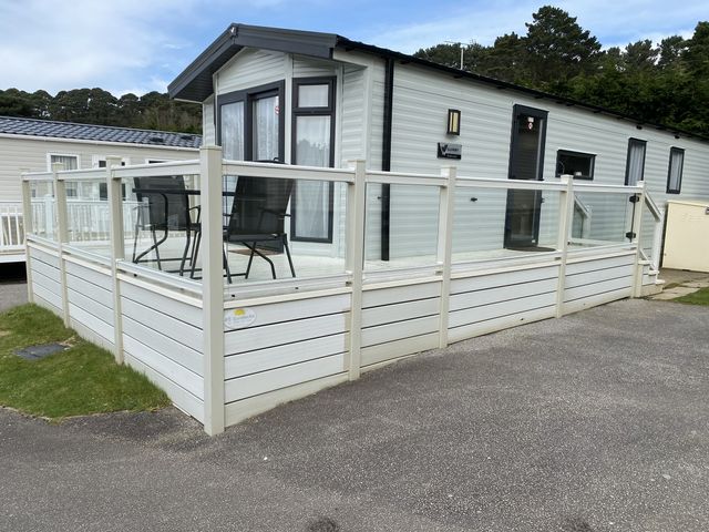 A caravan with a deck and chairs at WW15 Plot in Newquay
