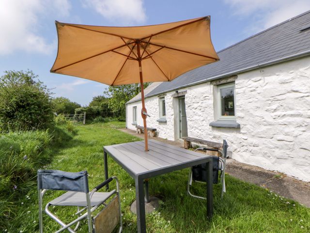 A table with umbrella and chairs outside a cottage at Rhos Y Clegyrn Goodwick