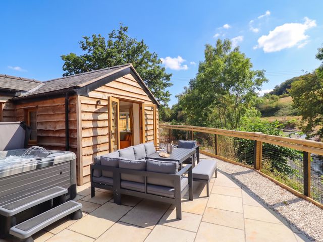 An outdoor seating area with a hot tub and a cabin at Bridge Farm Pontyblew near Chirk