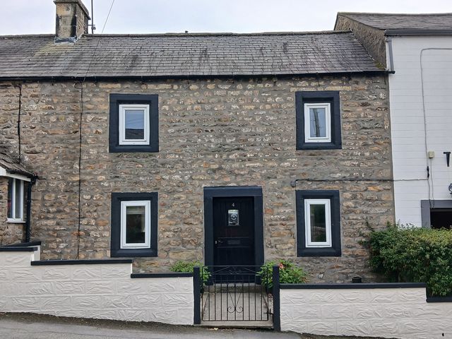 A house with stone walls and a black door at 4 Oak Cottages in Bentham, Yorkshire