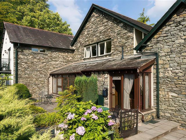 An outdoor view of a stone house with a patio and garden at The Gallery in Windermere