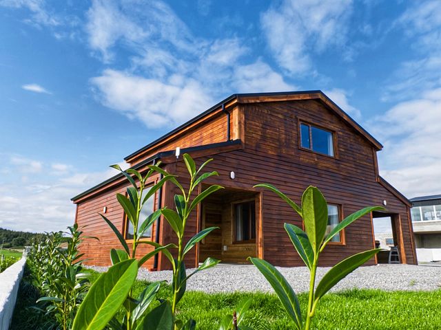 A wooden house with windows and a door surrounded by grass and gravel at Fisherman Lodge No 2 in Enniskillen