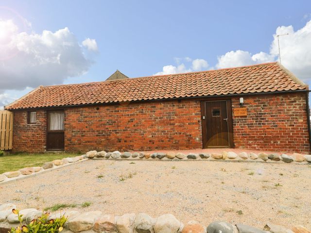 An exterior view of a cottage with a brick wall and gravel area at Honeybee Cottage in Hull