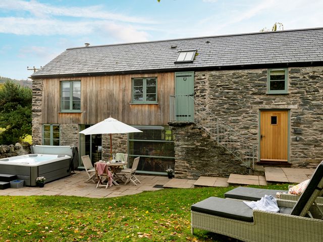An outdoor area with a hot tub and patio furniture at Shepherds Cottage in Llandrillo