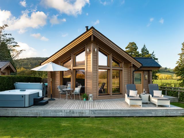 An outdoor area with a hot tub and seating at Lagom Log Cabin in Llandrillo