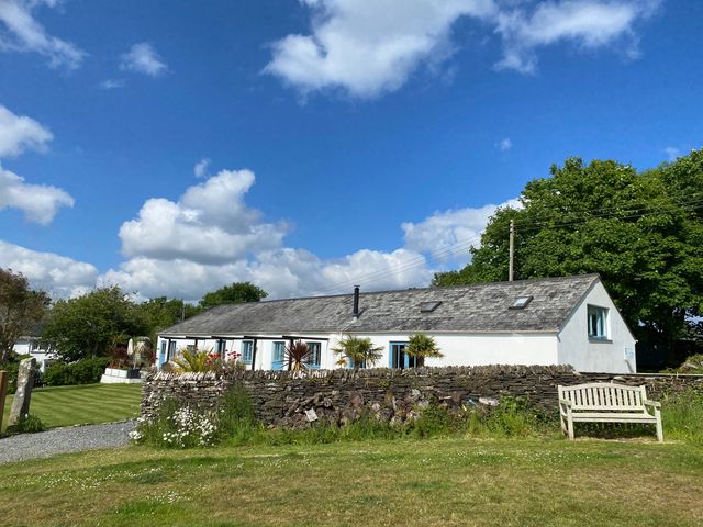 A house with a bench and trees at The Cowshed in Portscatho