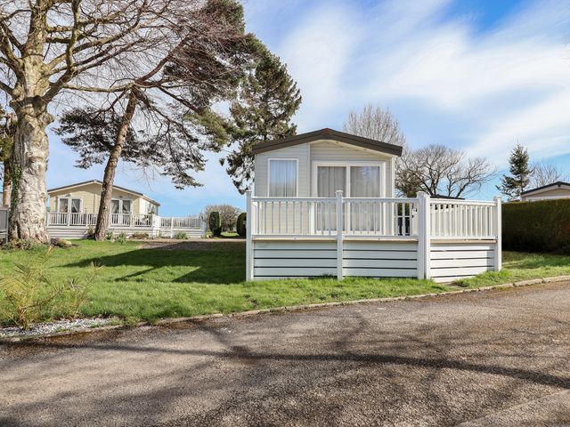 A caravan with a deck at Woodlands Hall Caravan Park near Ruthin