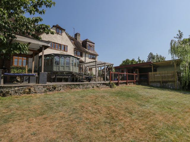 A garden with a house and deck area at West Down Country House South Molton