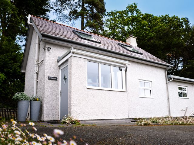 An exterior view of a cottage with flowers and planters at Eryri View Retreat in Llangoed near Beaumaris