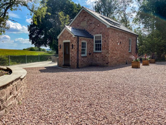 A brick house with planters in an outdoor area at Broadmoor Chapel Hereford