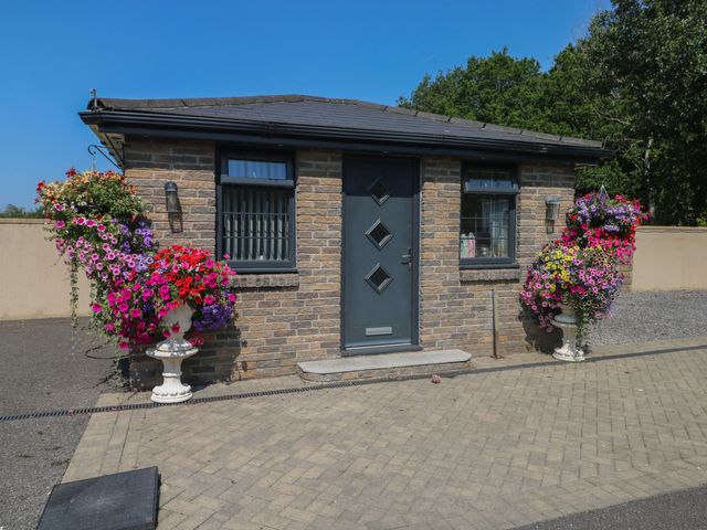 A brick building with a front door and flower pots at Annexe @ Meadows Farm, Gorseinon