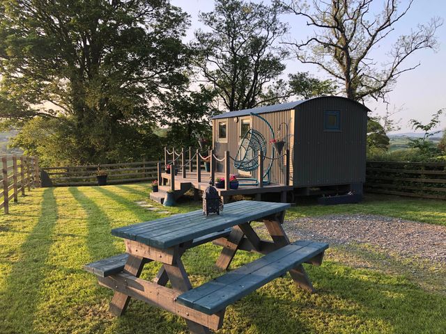 An outdoor area with a shepherd's hut and a bench at The Peacock Shepherds Hut at Hafoty Boeth, Corwen