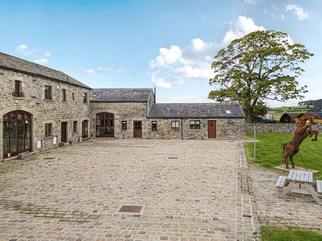 An outdoor area with stone buildings and a tree at Orcaber Farm Barn in Lancaster