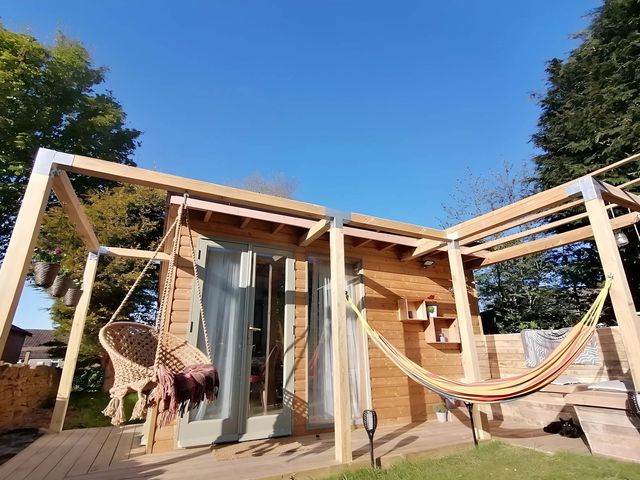 An outdoor area with a wooden cabin, hammock, and hanging chair at Stone Moor Lodge, Justin's Peak District Base Camp, Sheffield
