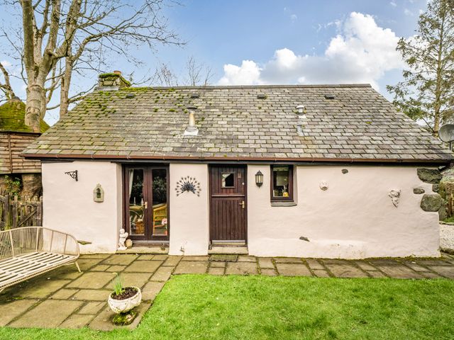 A cottage with a door and window surrounded by a garden at Converted Stone Barn -20 Acres - Farm Animals! in Corwen