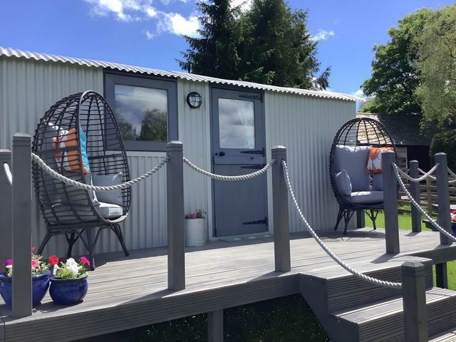 A deck with hanging chairs and door at The Shepherds Hut at Hafoty Boeth Corwen